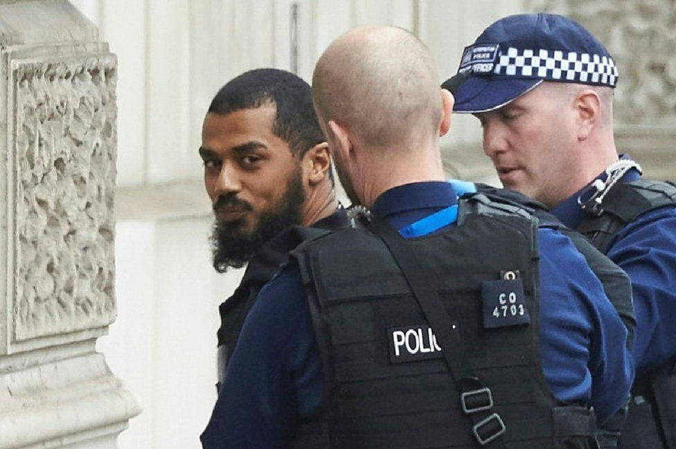 Firearms officers from the British police detain a man on Whitehall near the Houses of Parliament in central London