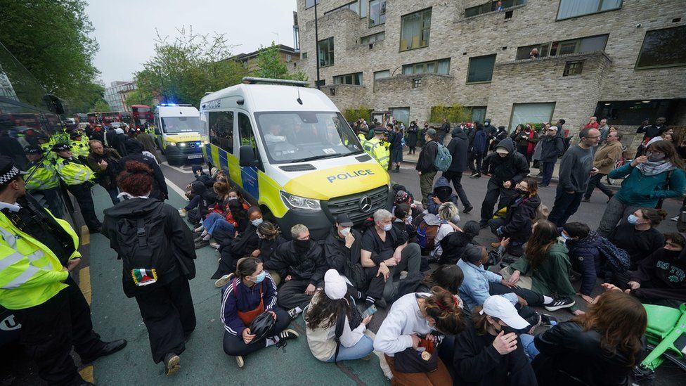 Protesters sat in front of a police van containing protesters