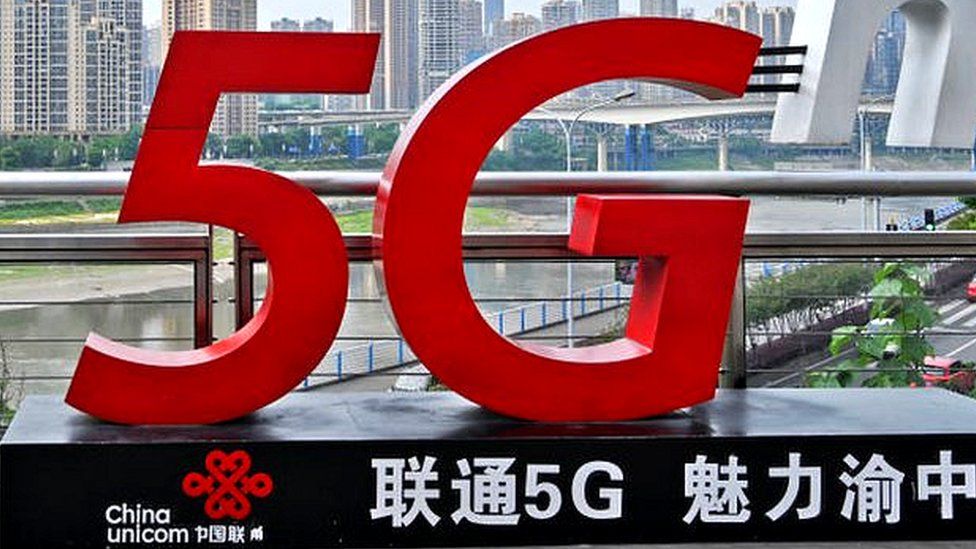 A woman stands beside a China Unicom 5G sign in Chongqing, China.