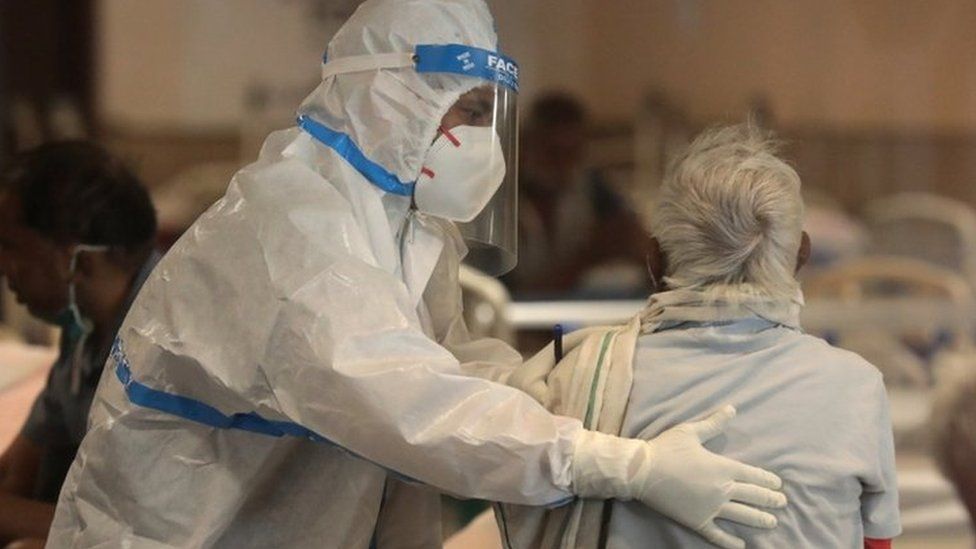 An Indian doctor wearing PPE examines a patient at a hospital in Delhi on 13 April 2021