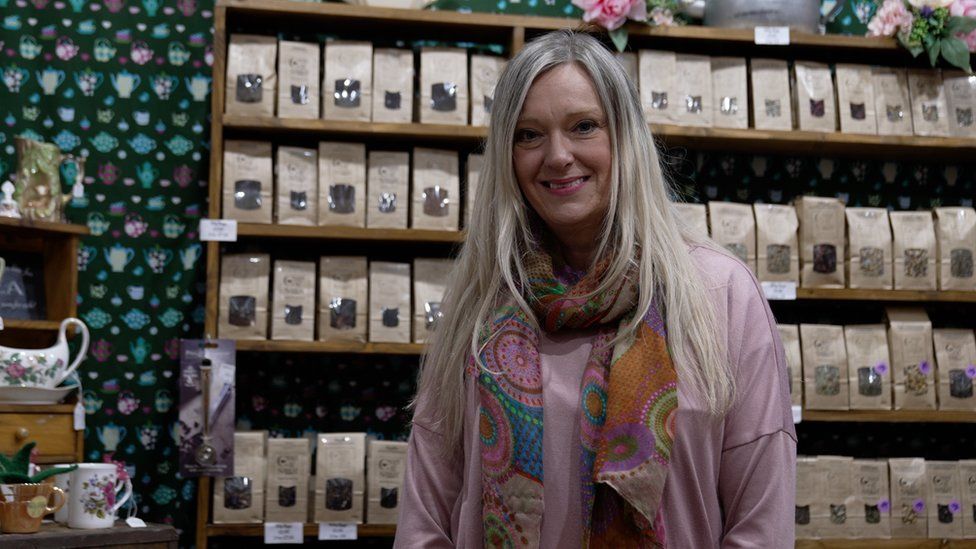 Gail Hannan standing in the tea shop by rows of shelves holding bags of tea