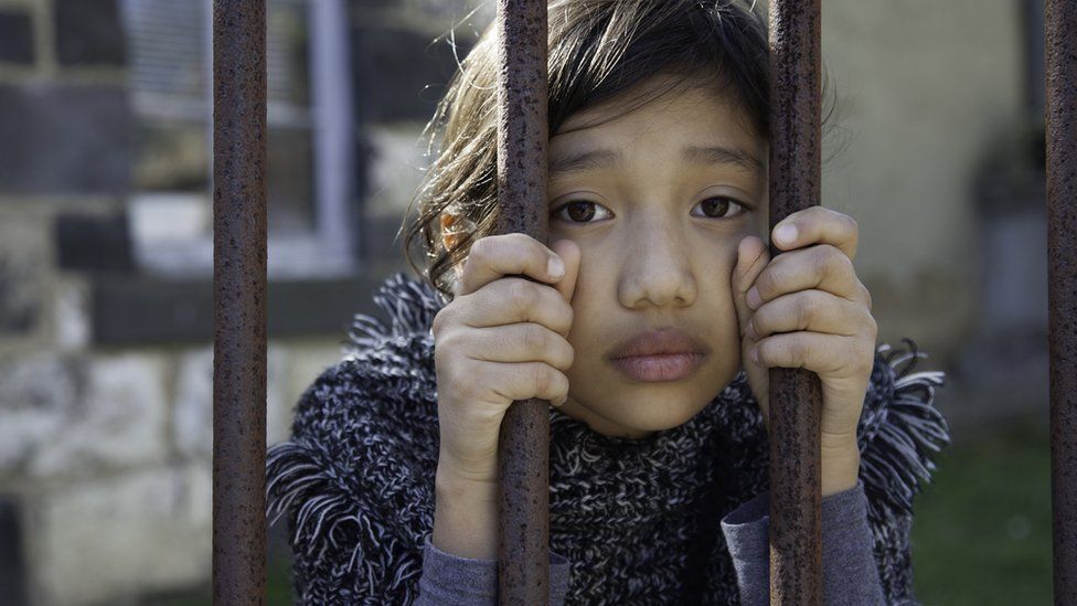 A girl holds prison bars