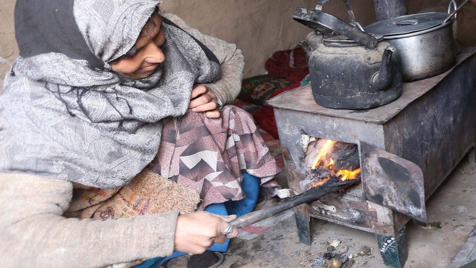 Afghan woman cooking on wood-burning stove