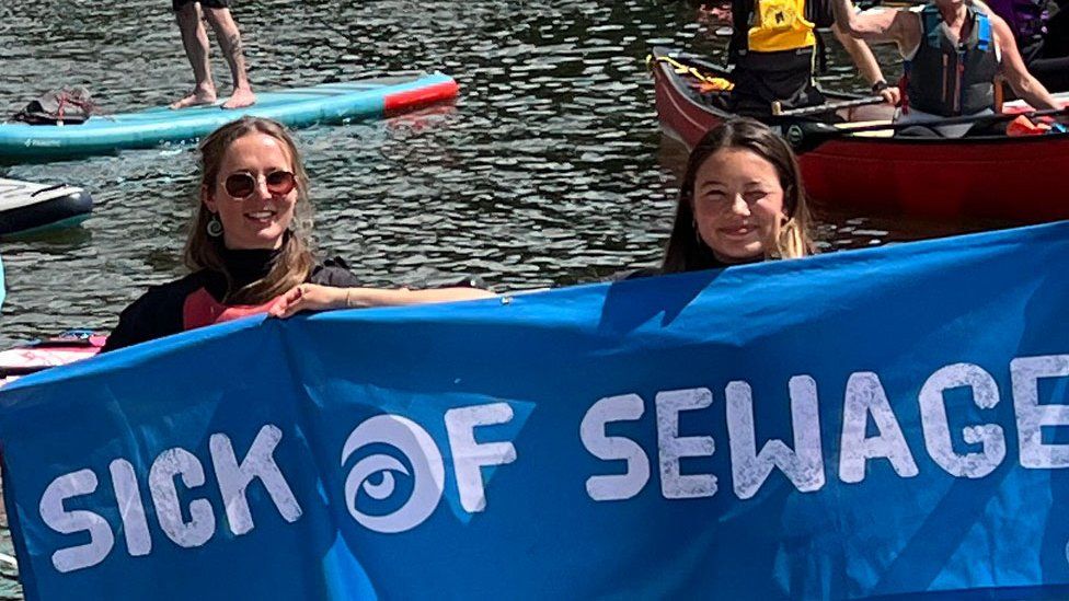 Two women with Sick of Sewage Sign, at Bedford