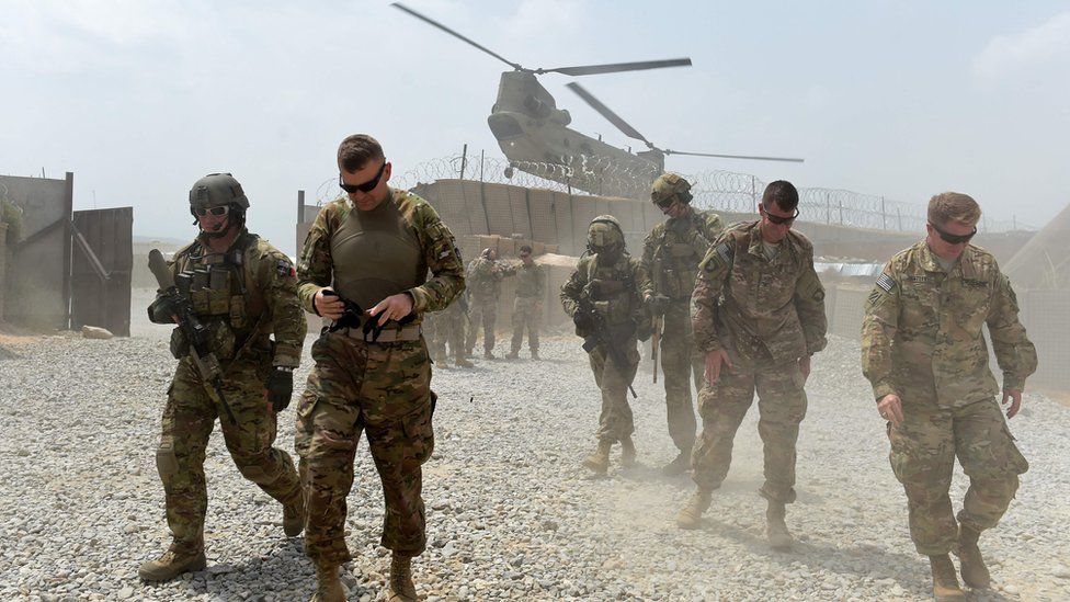 US soldiers walk by as a Nato helicopter flies overhead at a coalition base in the Khogyani district in the eastern Afghan province of Nangarhar