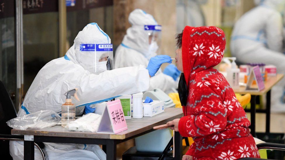 Медицинский работник берет мазок у местного жителя для анализа на нуклеиновую кислоту COVID-19 13 марта 2022 года в Чанчуне, провинция Цзилинь, Китай.