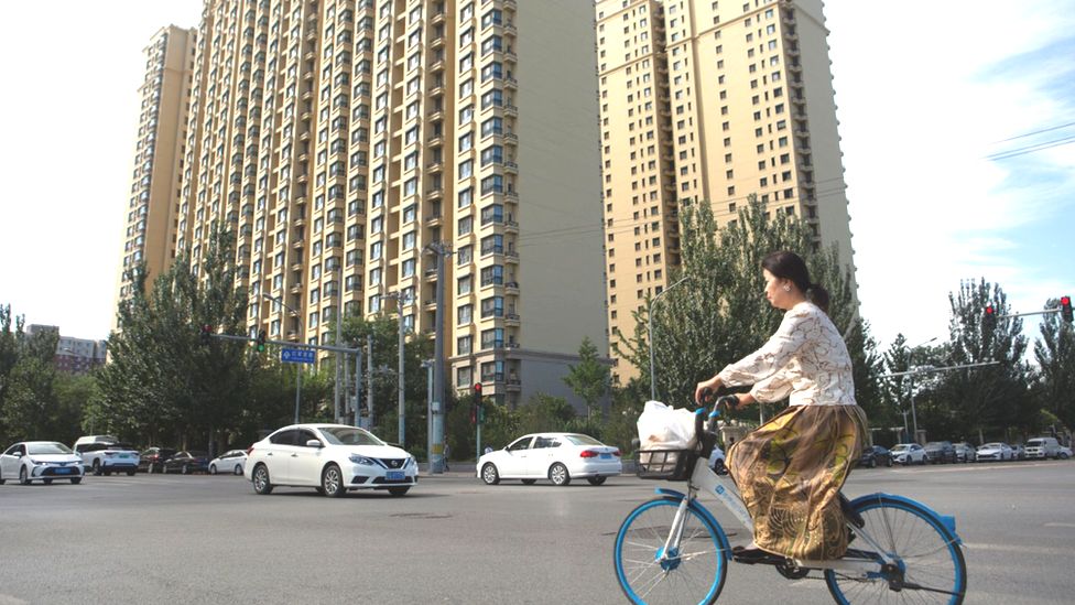 A woman rides a bicycle past an Evergrande housing complex in China's capital Beijing on 28 September 2023