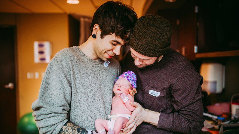 Baby Uma held by her parents Elliot Dougherty and Matthew Eledge.