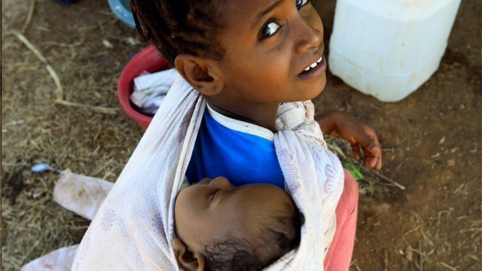 An Ethiopian refugee child from Tigray carries her sibling in the Um-Rakoba, Sudan. Photo: December 2020
