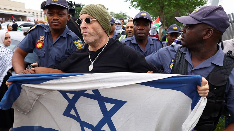 A demonstrator, holding an Israeli flag, is removed by police officers, at a protest in support of Palestinians outside the US embassy in Johannesburg, South Africa, 11 October 2023