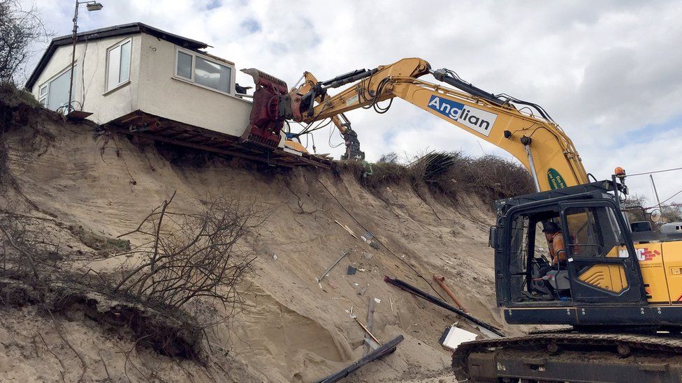 A home teetering on the edge of a cliff being demolished in Hemsby, Norfolk.