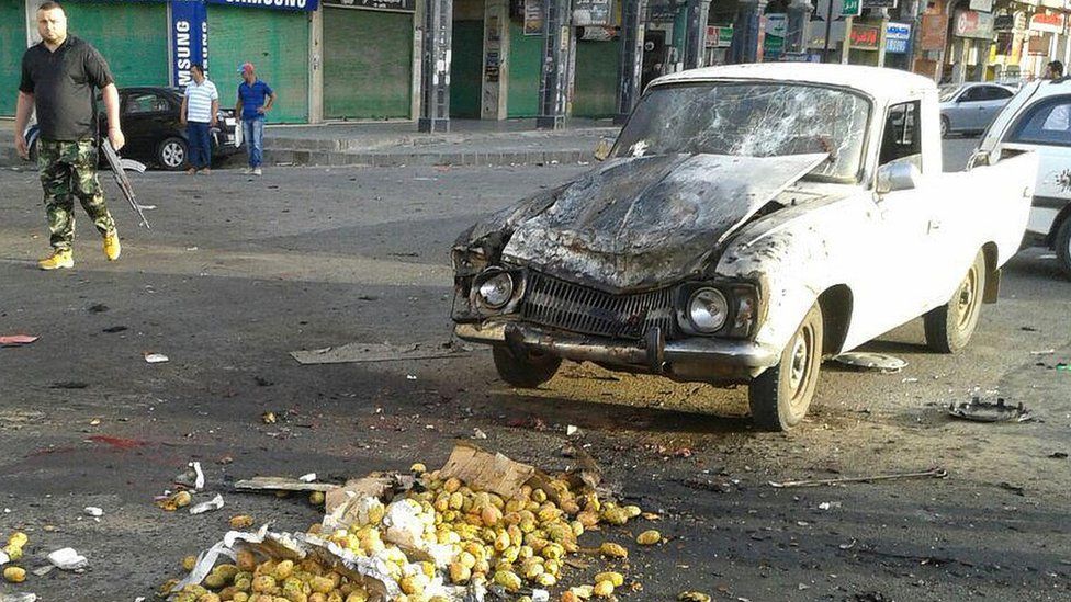 Picture from Syrian news agency (Sana) on July 25, 2018 shows a member of the security forces walking past a truck damaged in a suicide attack in Suweida