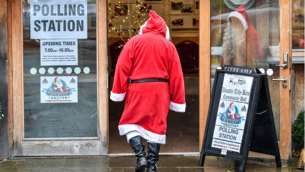 Santa goes to vote in Dunster Tithe Barn near Minehead, Somerset