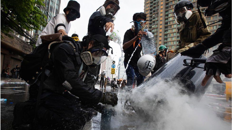 Protesters put out a tear gas grenade at Din Daeng intersection during the demonstration in Thailand, August 2021.