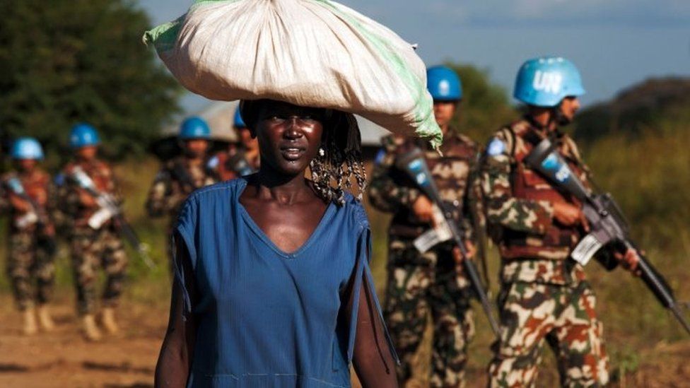 A displaced woman carries goods as UN peacekeepers patrol in Juba. Photo: 4 October 2016