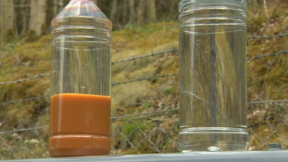 Two bottles, one containing the orange metallic sludge, the other clean water