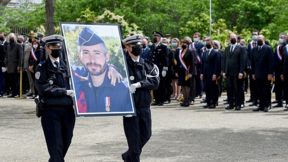 Французские полицейские несут портрет полицейского Эрика Массона во время церемонии в его честь