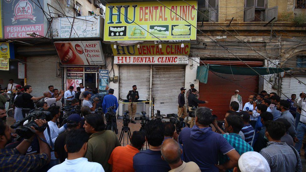Pakistani security officials inspect the scene after an unidentified assailant opened fire inside a dental clinic run by Chinese nationals, in Karachi, Pakistan