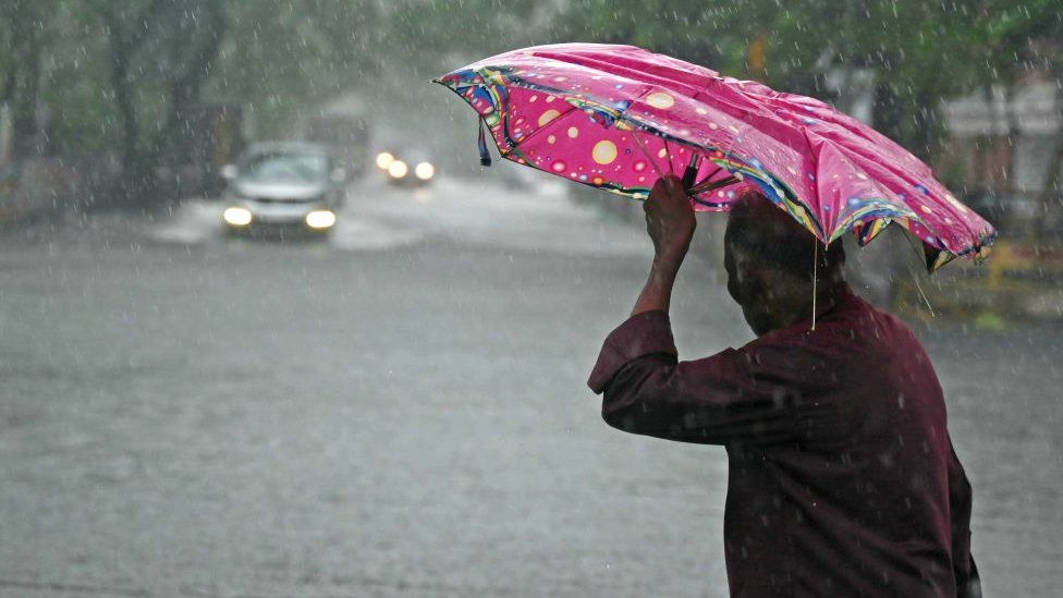A man takes shelter under an umbrella in Chennai