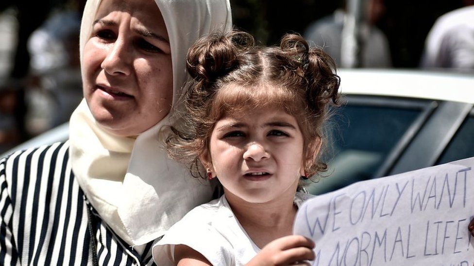 A Syrian girl holds a placard reading in English and German 'We only want a normal life' outside the German embassy in Athens on July 19, 2017.