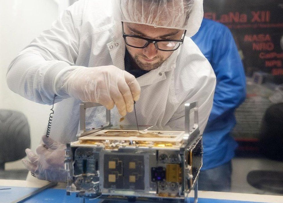 Mechanical engineer Joel Steinkraus makes an adjustment to a CubeSat