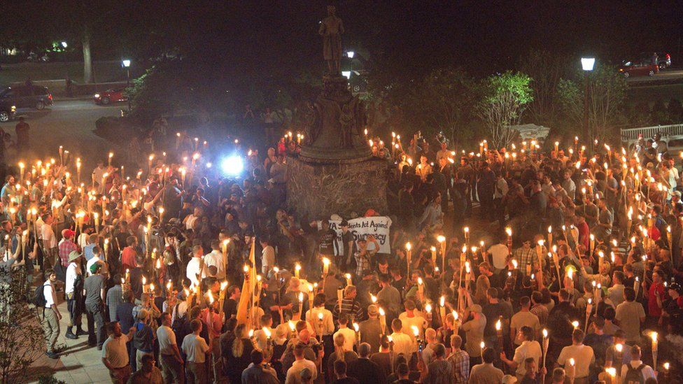 White nationalists carry torches around a statue of Thomas Jefferson on the grounds of the University of Virginia, surrounding a smaller group of counter protesters, 11 August 2017