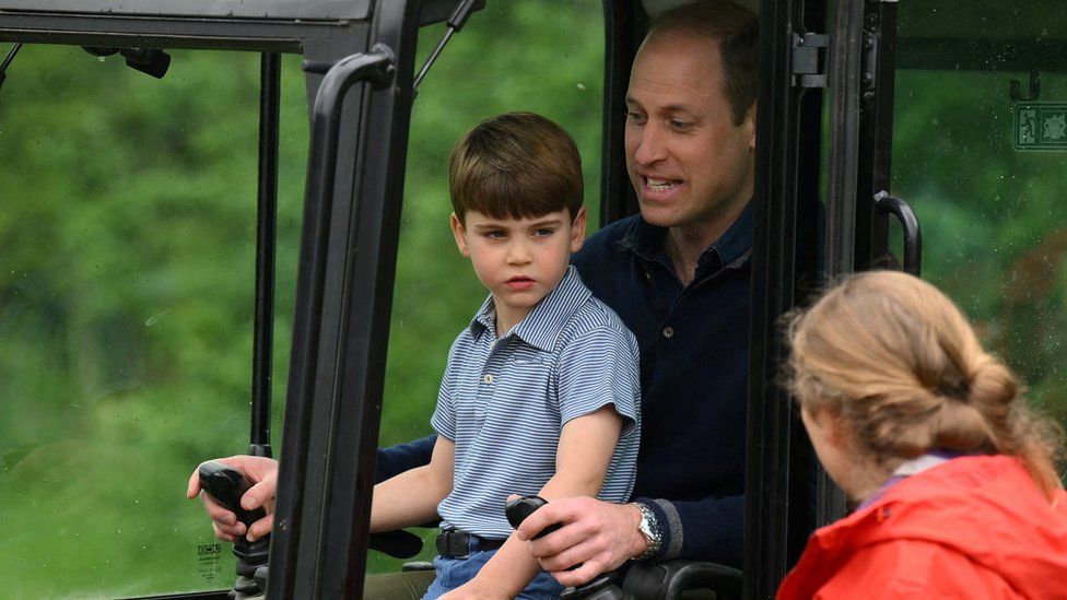 Britain's Prince William, Prince of Wales is helped by Britain's Prince Louis as he uses an excavator while taking part in the Big Help Out, during a visit to the 3rd Upton Scouts Hut in Slough, west of London