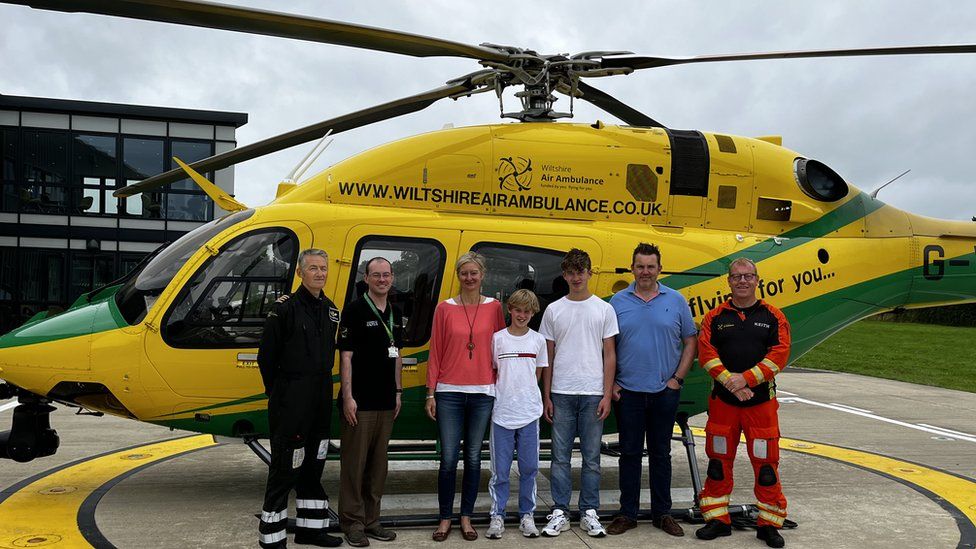 Maxi and the family stood on the helipad in front of a Wiltshire Air Ambulance helicopter