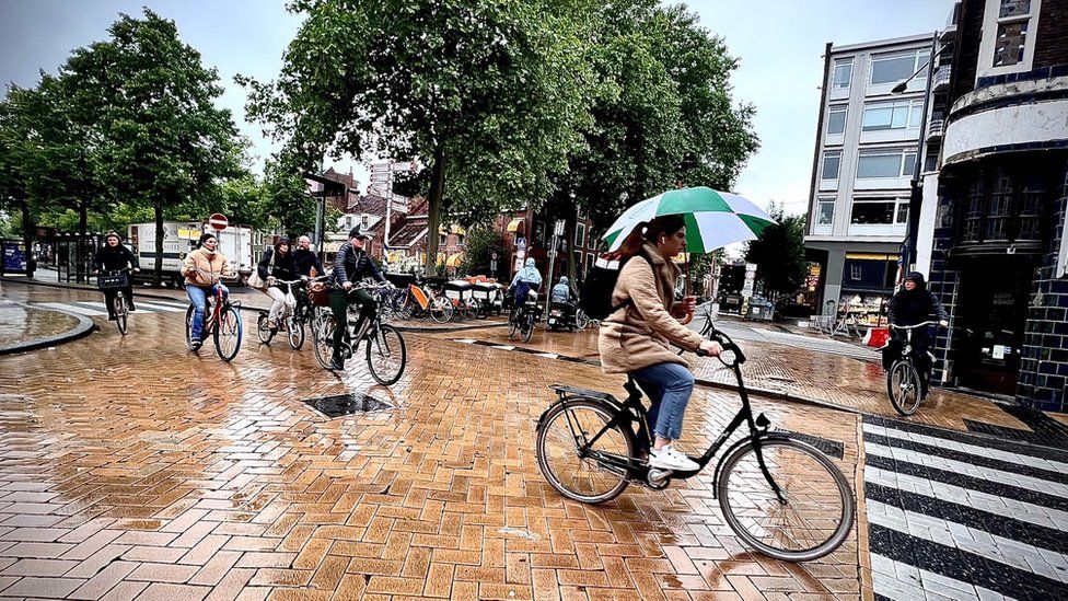 Люди на велосипеде под дождем в Нидерландах