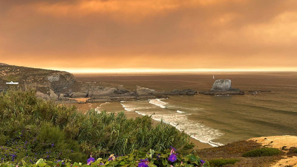 Sky tinged with orange over Portugal beach due to wildfire