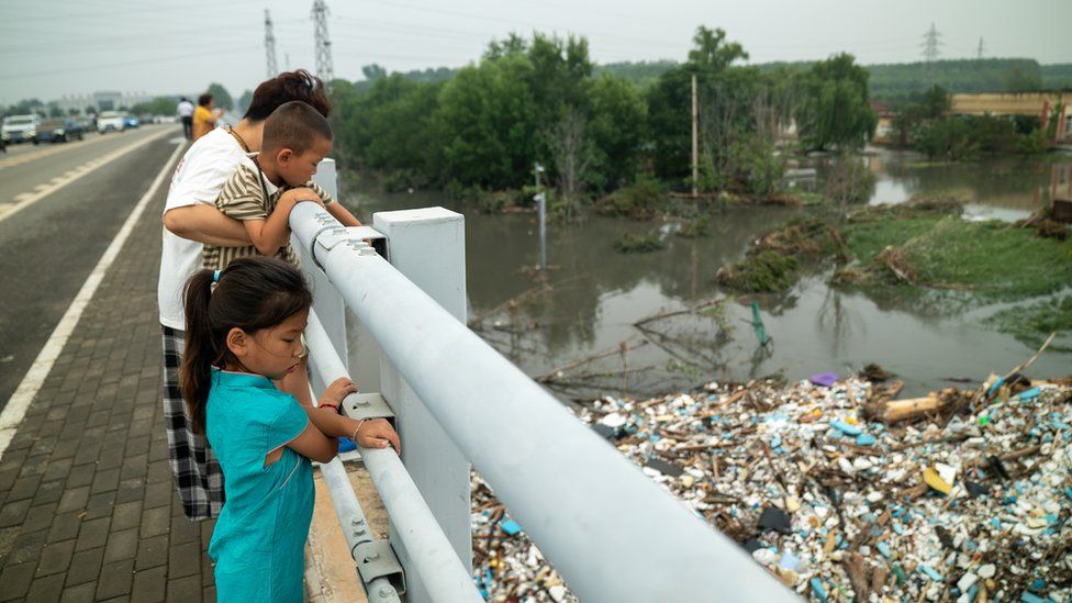 A family looking at an island of rubbish washed ashore by the flood