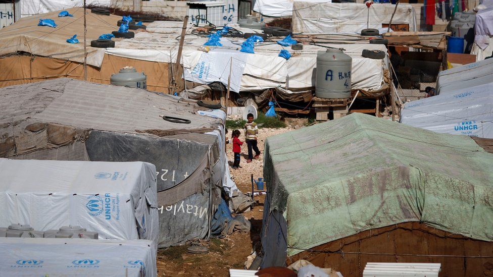 Syrian refugees outside tents in a camp in east Lebanon