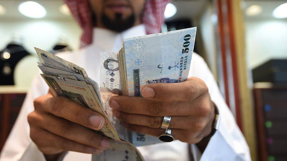 A man counts Saudi riyal banknotes in Riyadh.