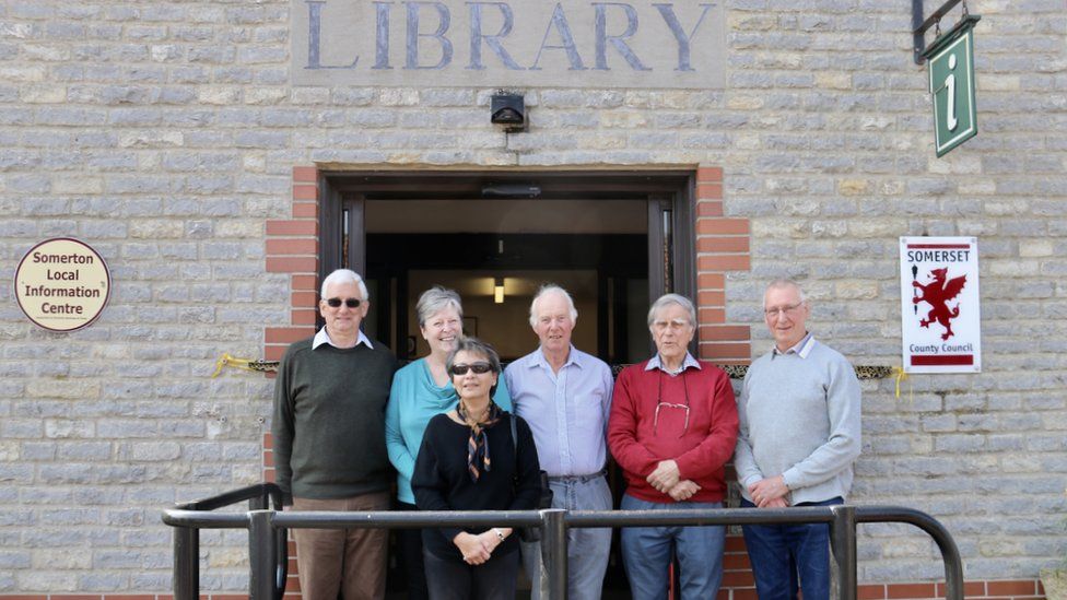 Six people stood in front of a library sign