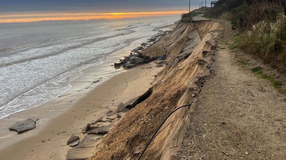 Concrete roadway collapsed and fresh erosion on cliff face.