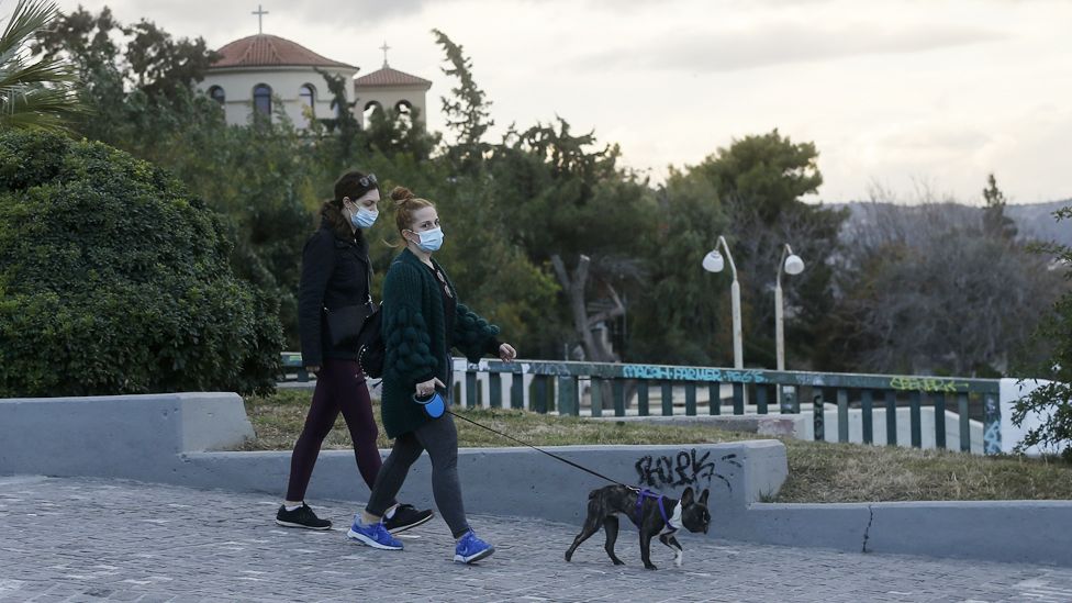 Люди в масках выгуливают собаку в Афинах, Греция