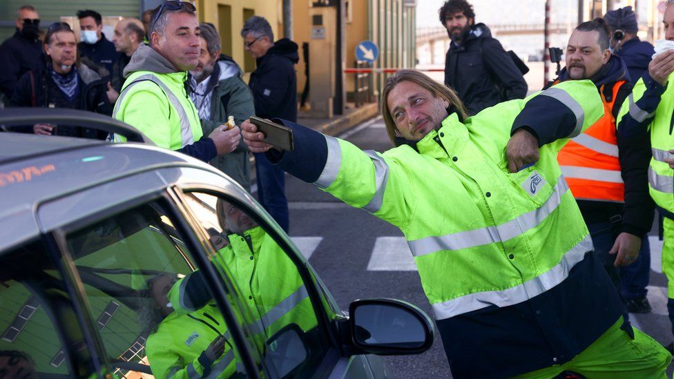 A person takes a selfie as port workers gather outside the entrance of the major port of Trieste to protest against the implementation of the COVID-19 health pass