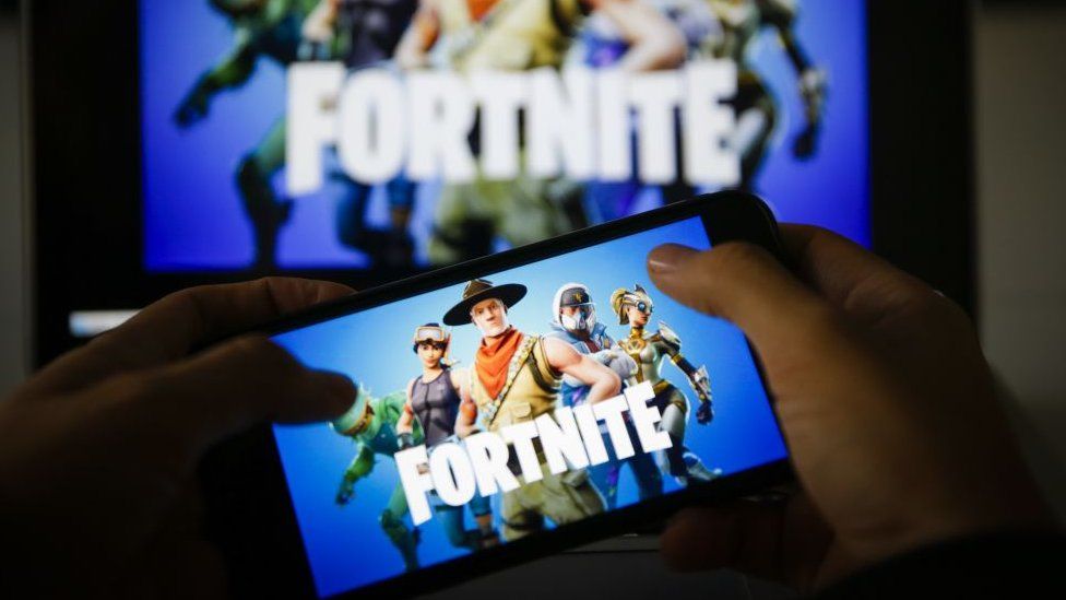 Fortnite on a smartphone and larger screen in the background
