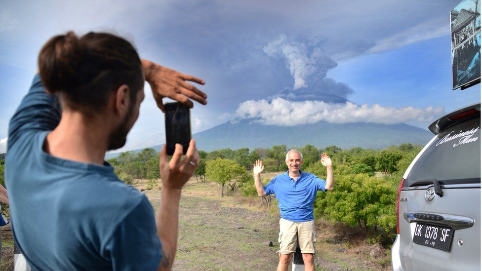 Tourist poses for a photo in front of Mt Agung