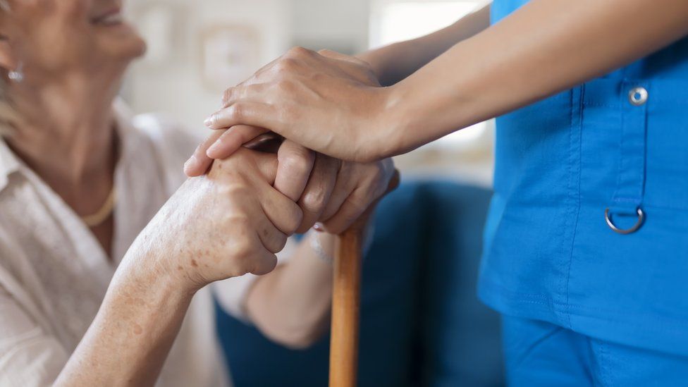 Care home worker holding a resident's hands