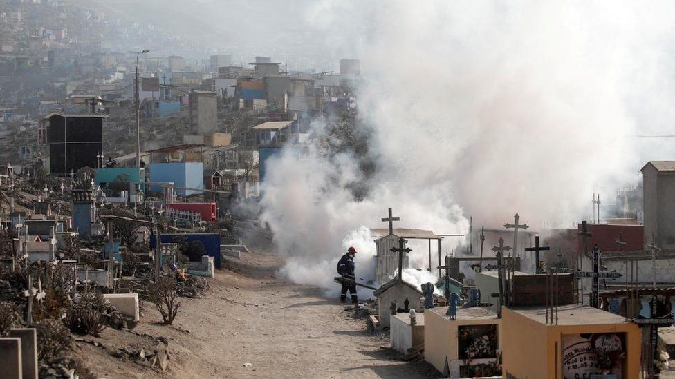 Огромное облако пара, когда рабочий опрыскивает могилы на кладбище в Лиме для защиты от распространения лихорадки денге