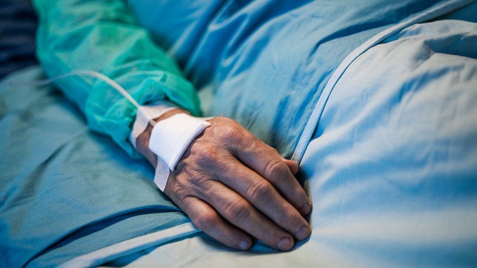 A close up of a male patient lying in a hospital bed.