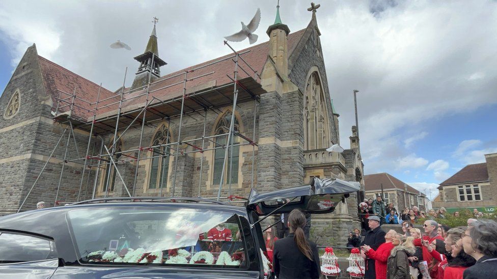 Doves are released as the coffin leaves the church