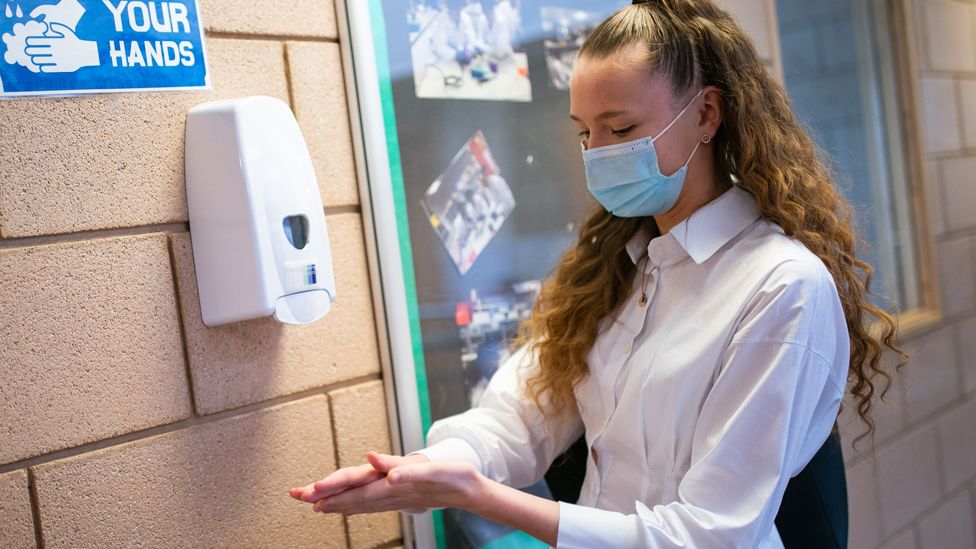 A student rubs in hand sanitiser before entering a classroom in Croydon, on 8 March 2021