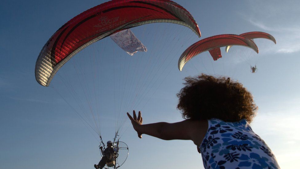 A girl reaches up towards military paragliders in Casablanca, Morocco - Saturday 30 September 2017
