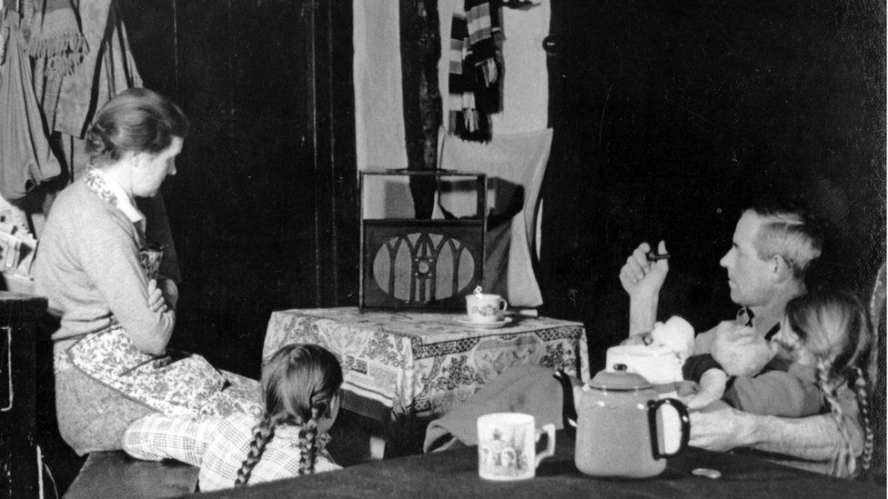 a family around a wireless radio, listening to the news