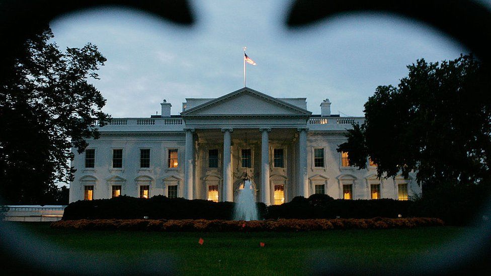 The White House photographed at dawn through the frame of a fence