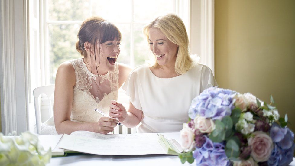 Two brides signing a wedding book