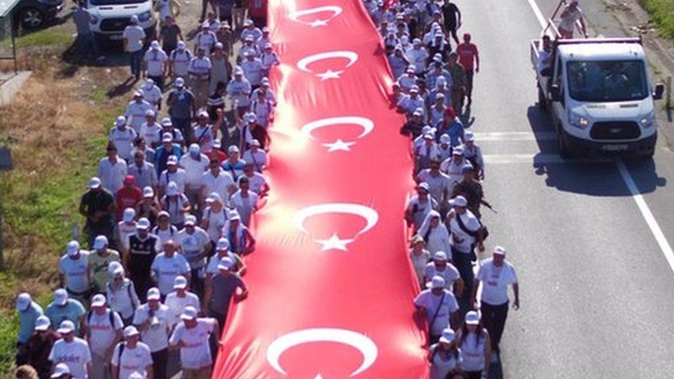 Thousands of supporters hold a long Turkish national flag on the march to Istanbul