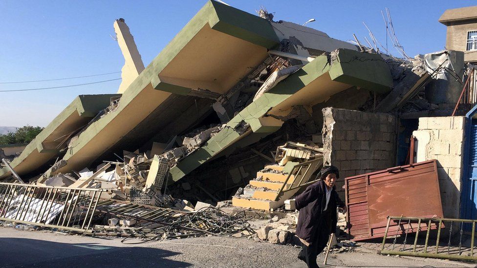 Un hombre camina frente a un edificio aplastado en Darbandikhan, Irak